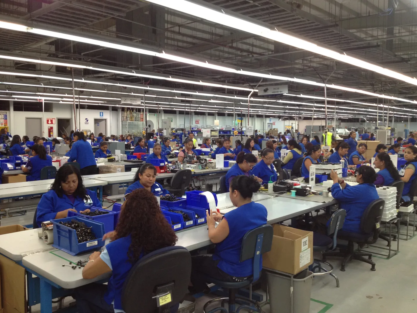 Piso de producción de una planta de manufactura, con alrededor de cien personas trabajando